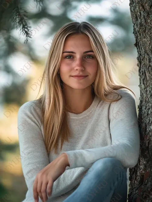 Ragazza giovane e sorridente con capelli biondi, posa naturale accanto a un albero in un ambiente sereno.