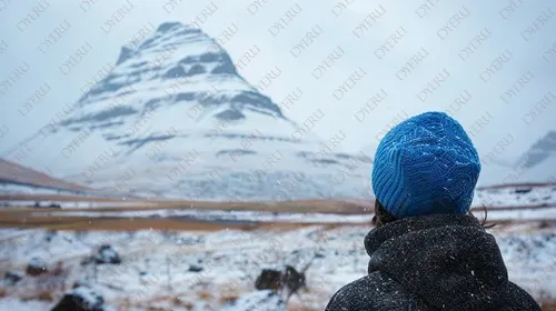 Giovane avventuriero con berretto blu ammirando il paesaggio innevato di Kirkjufell in Islanda