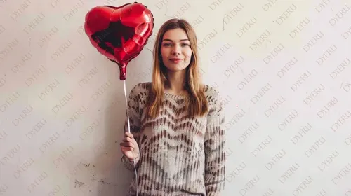 Giovane donna sorridente con palloncino a forma di cuore rosso