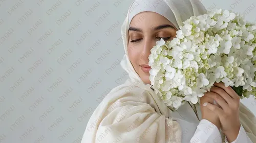 Giovane donna musulmana con velo che abbraccia un bouquet di fiori bianchi